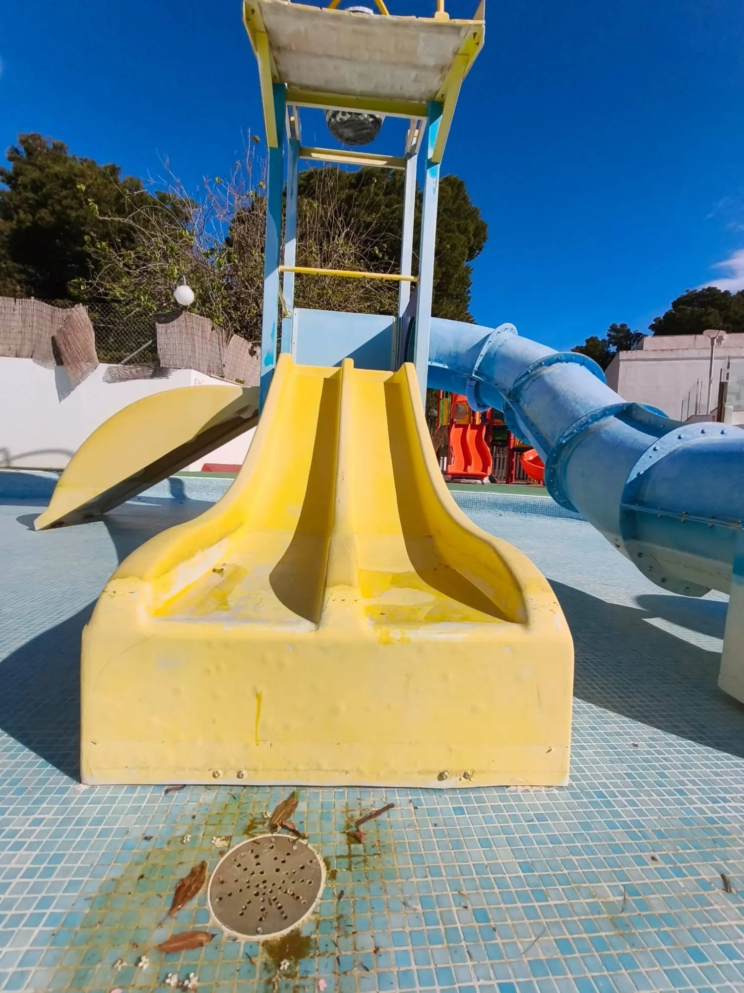 Water play tower with faded, worn yellow slide before restoration
