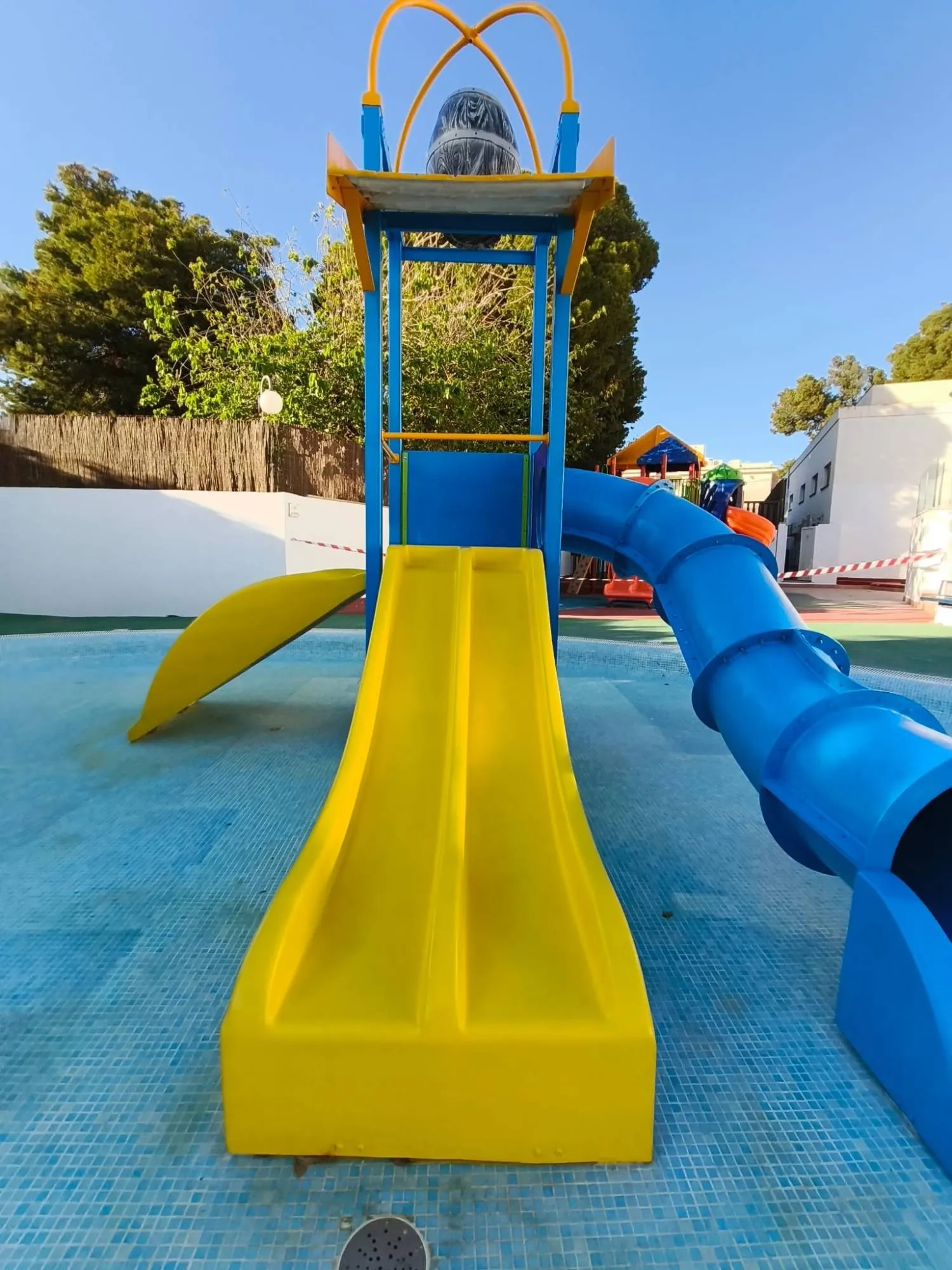The same water play tower after restoration, with bright yellow and blue slides