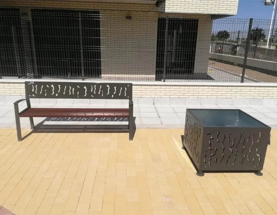Wood and steel bench with a perforated back next to a matching planter