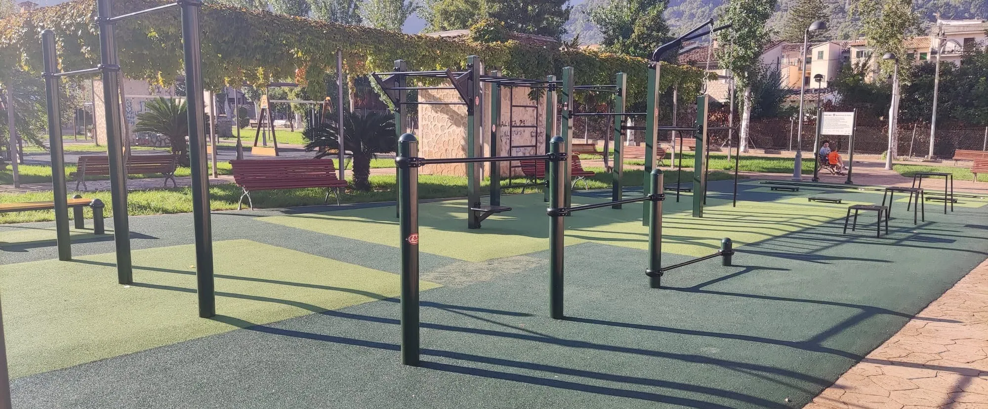 Parque de calistenia con estructuras negras y pavimento de caucho verde
