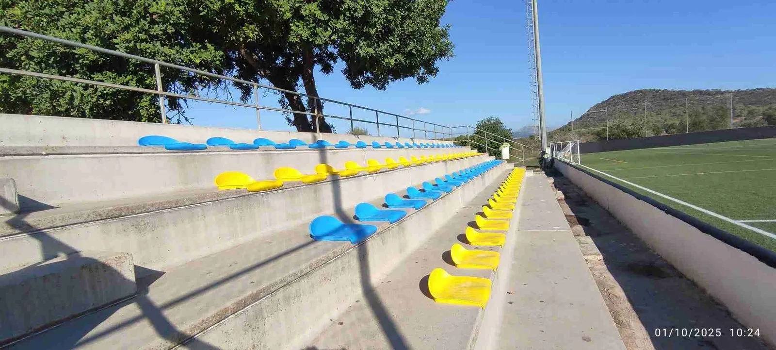Grada de hormigón con asientos amarillos y azules
