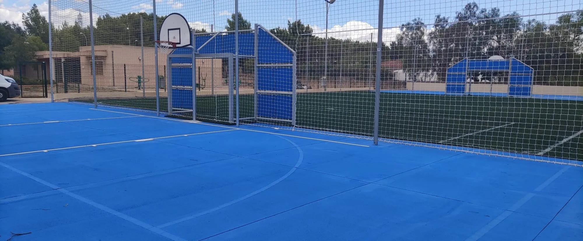 Pista multideporte azul con portería-canasta combinada y campo de césped artificial
