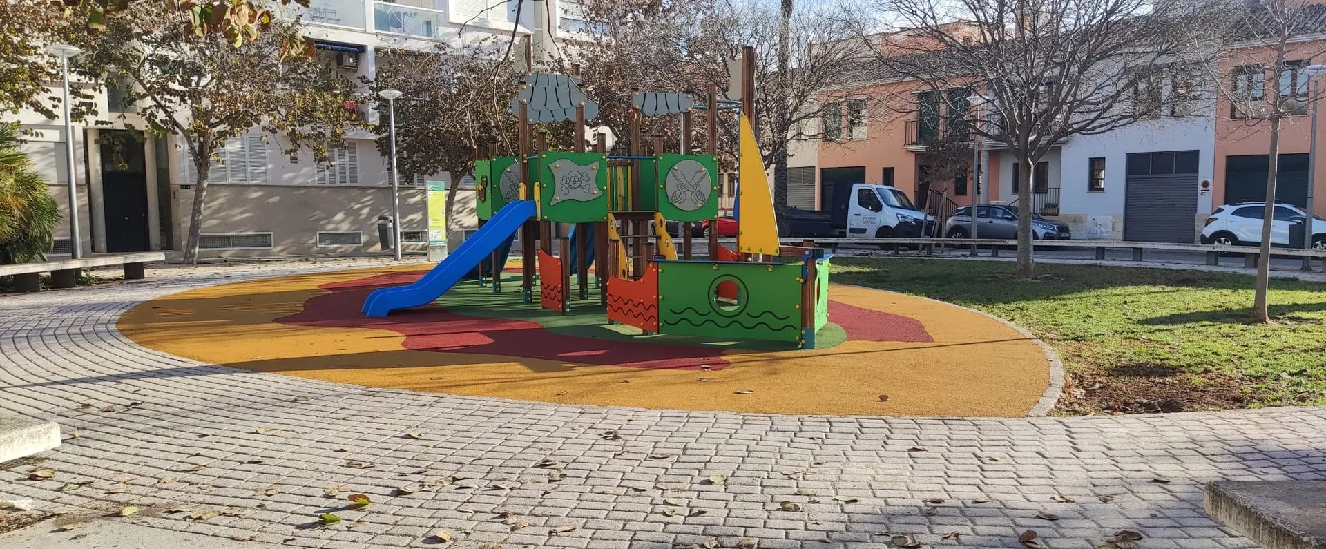 Parque infantil temático de barco pirata sobre pavimento de caucho en una plaza