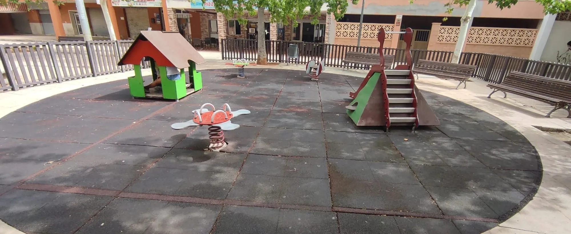 Playground with worn black rubber surfacing before renovation