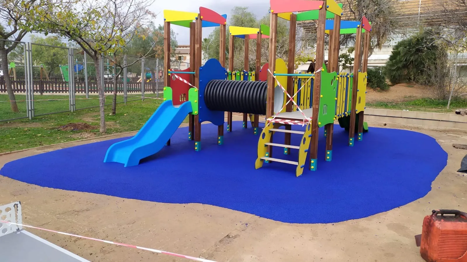 Torres de juego de madera con túnel y tobogán instaladas sobre pavimento de caucho
