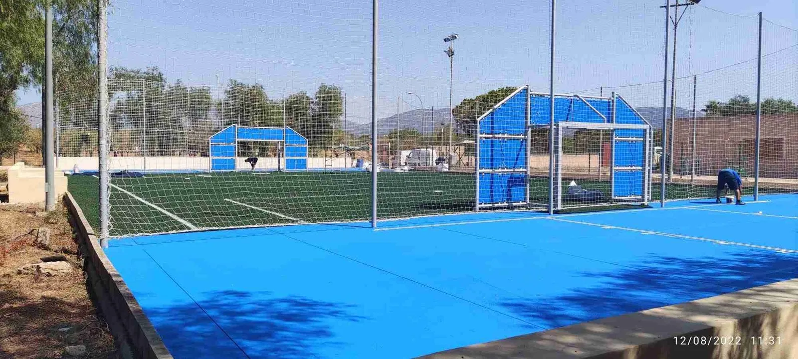 Pista deportiva azul con porterías y canasta de baloncesto