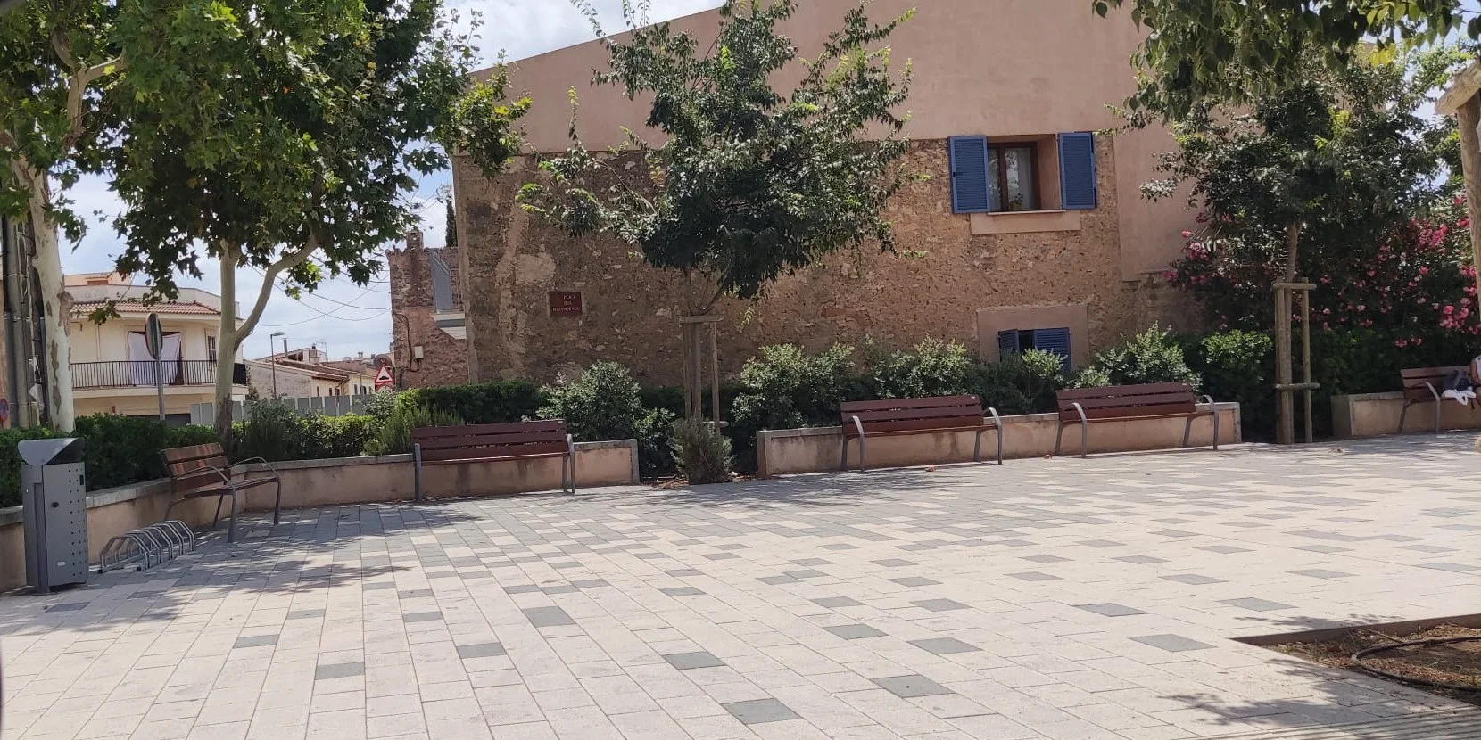 Town square with wooden benches, planters, a litter bin and bike racks