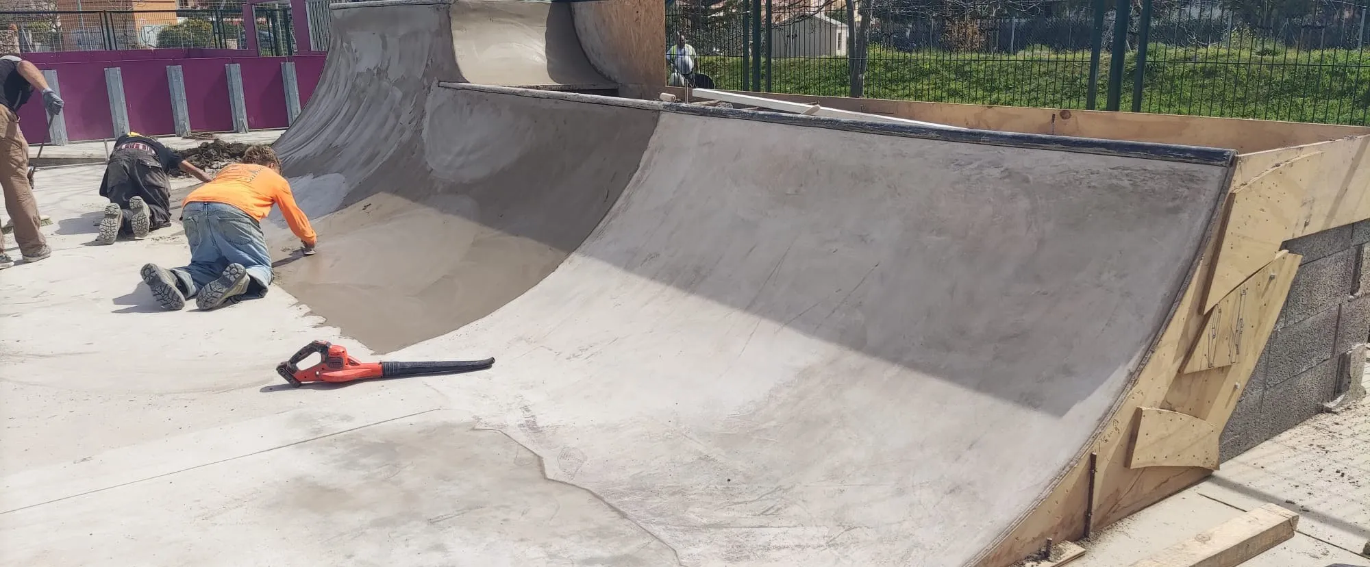 Equipo de montaje alisando el hormigón de una rampa de skatepark
